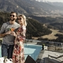 Paar genießt Aperol vor Infinitypool mit Panoramablick auf Berge.
