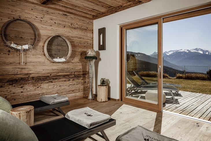 Ruheraum mit Holzverkleidung, Liegen und Bergblick durch große Fenster.