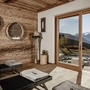 Ruheraum mit Holzverkleidung, Liegen und Bergblick durch große Fenster.
