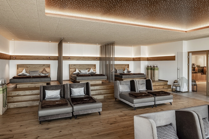 Moderner Ruheraum mit Holzbetten und Liegestühlen in neutralen Farben.