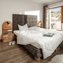 Helles Doppelzimmer mit Bett, Holzmöbeln und Blick auf die Wiesen.