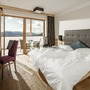Doppelzimmer mit Bett und Balkonausblick auf Berge.