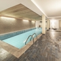 Innenansicht eines modernen, beleuchteten Schwimmbads mit Liegestühlen.