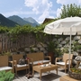 Terrasse eines Hotels mit Sitzmöbeln, Sonnenschirm und Bergblick.