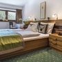 Gemütliches Schlafzimmer mit Doppelbett, Holzmöbeln und Fensteraussicht auf Berge.