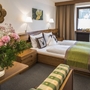 Gemütliches Hotelzimmer mit Doppelbett und Blumenarrangement.