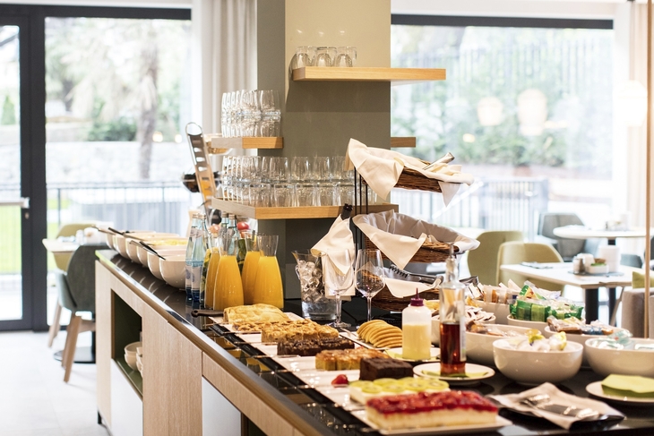 Frühstücksbuffet im Hotel mit Gebäck, Getränken und Geschirr.