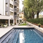 Außenbereich des Hotels Flora mit Pool und Liegen im Garten.