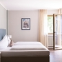 Helles Hotelzimmer mit Doppelbett und offenem Fenster.
