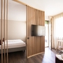 Modernes Schlafzimmer mit Doppelbett, Holzakzenten und großem Fenster im Flora Hotel & Suites.