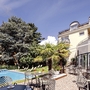Außenbereich der Hotel Villa Laurus mit Pool, Terrasse und Gartenmöbeln.