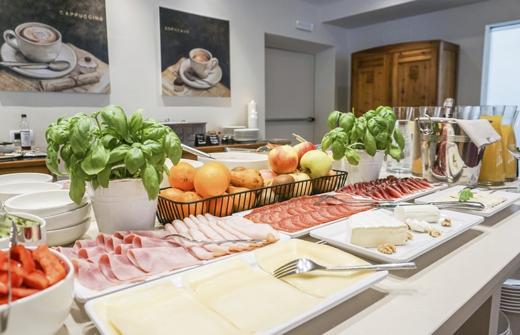 Frühstücksbuffet mit Aufschnitt, Käse, Obst und Pflanzen.