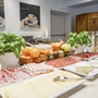 Frühstücksbuffet mit Aufschnitt, Käse, Obst und Pflanzen.