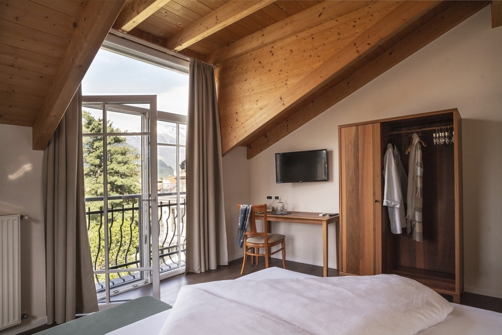 Doppelzimmer mit Holzbalkendecke, Balkon mit Bergblick, Schreibtisch und Schrank.