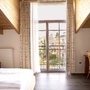 Helles Hotelzimmer mit Holzmöbeln und Balkonblick auf die Umgebung.