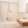 Modernes Badezimmer mit Badewanne, Waschbecken und Spiegel in heller Farbgebung.