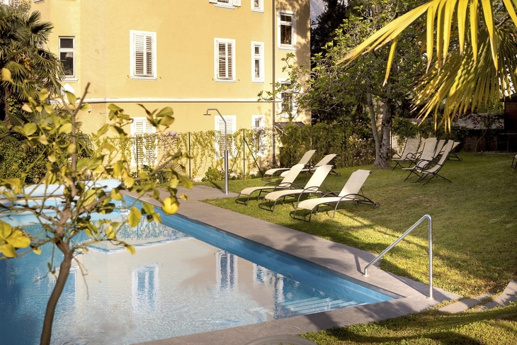 Gartenblick mit Pool und Liegestühlen im Hotel Villa Laurus in Meran.