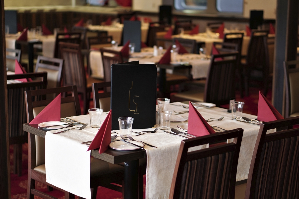 Ein elegant eingerichtetes Restaurant mit gedeckten Tischen und roten Stoffservietten.