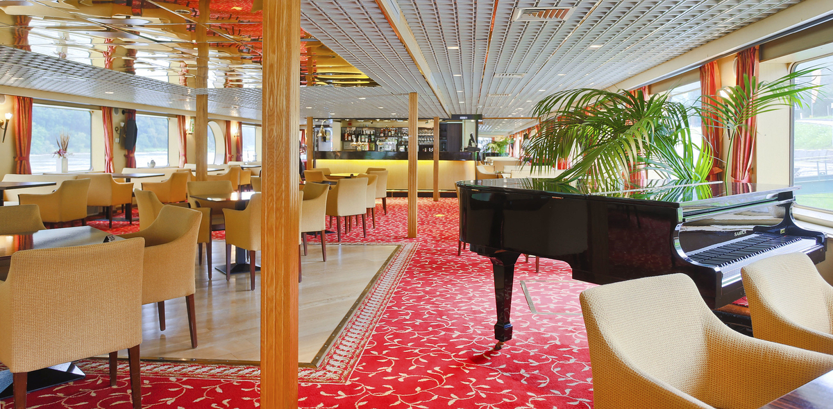 Eleganter Salon auf einem Schiff mit Klavier und gemütlichen Sitzgelegenheiten.