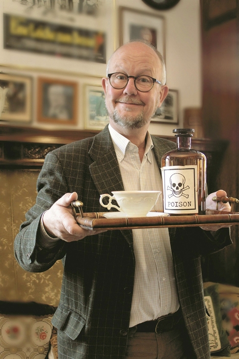 Mann hält Tablett mit Tasse und Flasche mit Totenkopfetikett.
