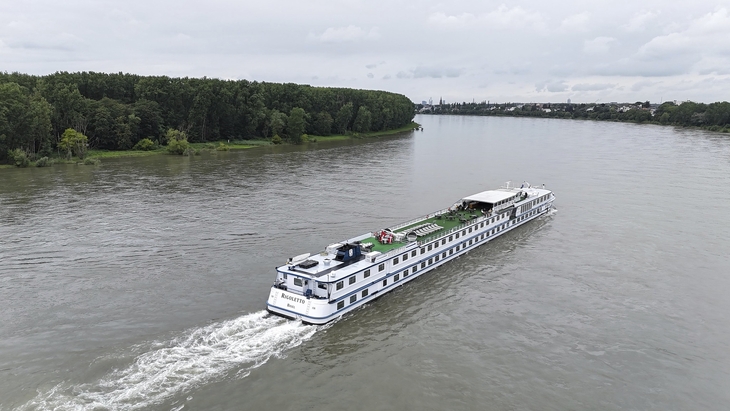 Kreuzfahrtschiff MS Rigoletto fährt auf einem Fluss, umgeben von Bäumen.