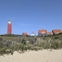 Leuchtturm auf Texel mit roten Dächern und Dünen im Vordergrund.