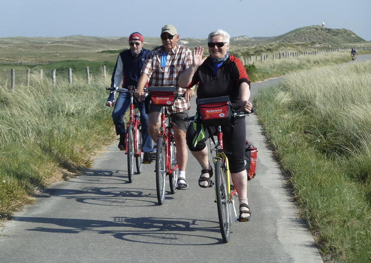 Gruppe von Erwachsenen fährt Fahrrad auf einem Weg durch eine grüne Landschaft.