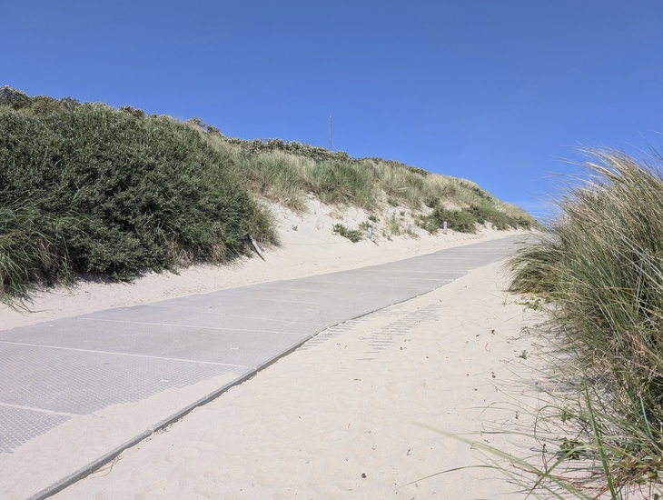 Sandweg durch Dünenlandschaft unter klarem Himmel