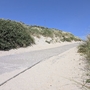 Sandweg durch Dünenlandschaft unter klarem Himmel