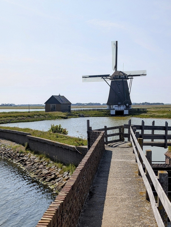 Windmühle in der Landschaft von Texel, Nordholland, mit Wassergraben im Vordergrund