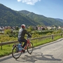 Person radelt auf einem Weg entlang einer Landschaft mit Hügeln und Häusern.