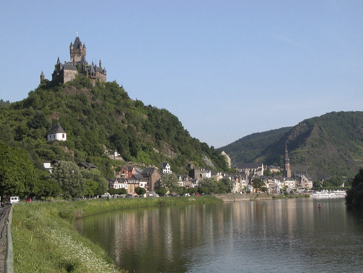 Burg Cochem auf Hügel, umgeben von Stadt und Flusslandschaft.