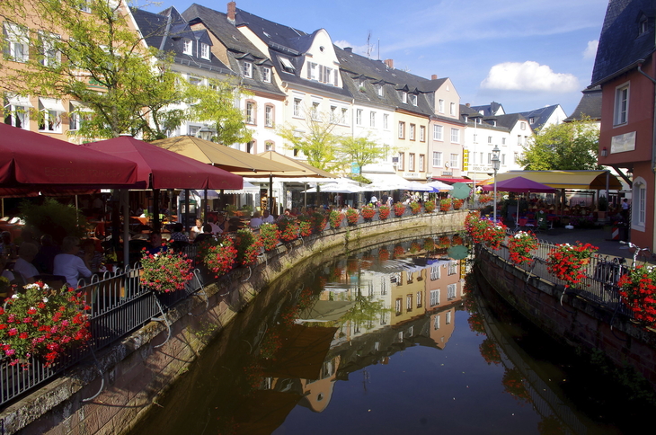 Kanal in Saarburg mit bunten Häusern und Blumen geschmückten Ufer.