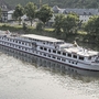Flusskreuzfahrtschiff MS Normandie auf einem Fluss vor grüner Uferlandschaft.