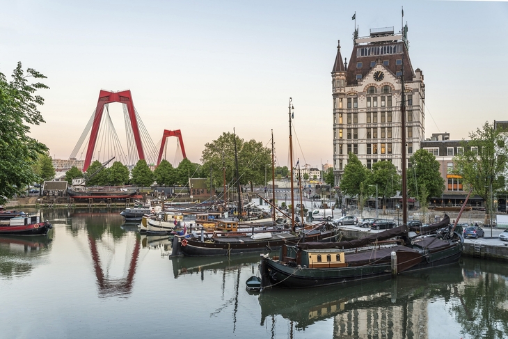 Alter Hafen in Rotterdam mit historischen Schiffen und der roten Brücke im Hintergrund.
