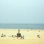 Strand mit Sandfläche und Spielgeräten, dahinter das Meer bei diesigem Himmel.