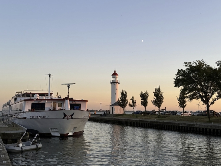 Schiff im Hafen von Hellevoetsluis bei Sonnenuntergang mit Leuchtturm im Hintergrund.