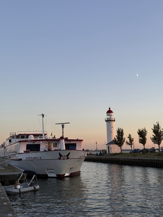 Ein Schiff im Hafen von c bei Sonnenuntergang neben einem Leuchtturm.