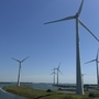 Windräder auf einem Deich in Zeeland, Niederlande bei klarem Himmel.