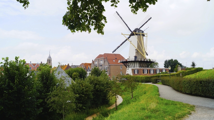 Windmühle in Willemstad, Zeeland, umgeben von grüner Landschaft und historischen Gebäuden.