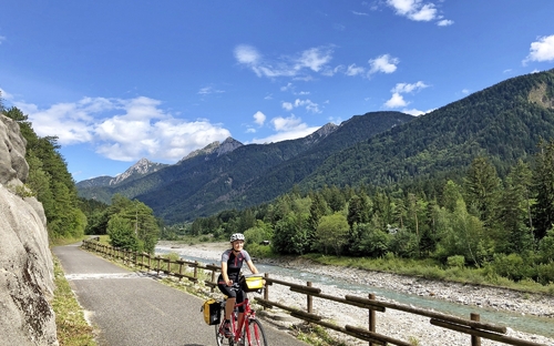 Radfahrer auf dem Alpe-Adria-Radweg in bergiger Landschaft bei sonnigem Wetter.