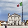 Historisches Gebäude in Udine mit italienischer Flagge im Vordergrund.
