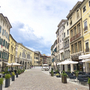 Straßencafé und historische Gebäude in einer Altstadt unter blauem Himmel