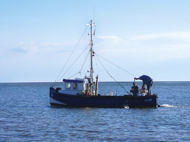 Fischerboot auf dem Meer bei Büsum unter blauem Himmel.