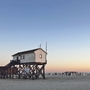 Pfahlbau und Strandkörbe am Strand von St. Peter-Ording bei Sonnenuntergang.