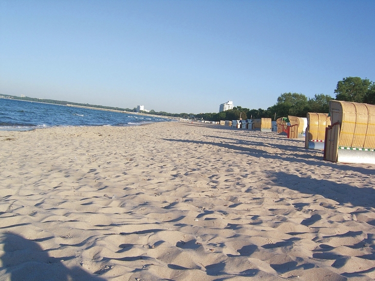 Sandstrand mit Strandkörben und Meerblick unter klarem Himmel.