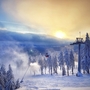 Winterliche Landschaft im Harz mit schneebedeckten Bäumen und Sessellift bei Sonnenuntergang.