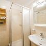 Helles Badezimmer mit Dusche, Waschbecken und Spiegel im Hotel Alpenrose.