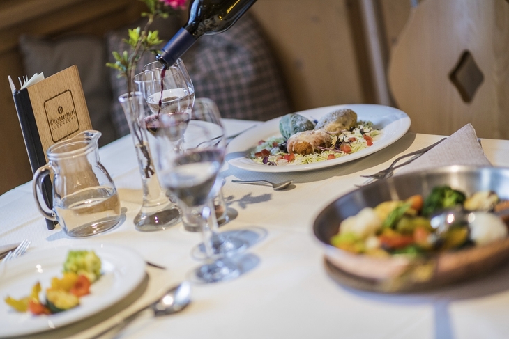 Ein gedeckter Tisch mit Wein und servierten Gerichten in einem Restaurant.