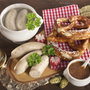 Weißwürste mit Brezel, Senf und Weizenbier auf einem Holztisch.